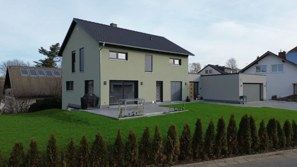 Haus Sophie: Einfamilienhaus mit grüner Putzfassade, Satteldach und angebauter Doppelgarage
