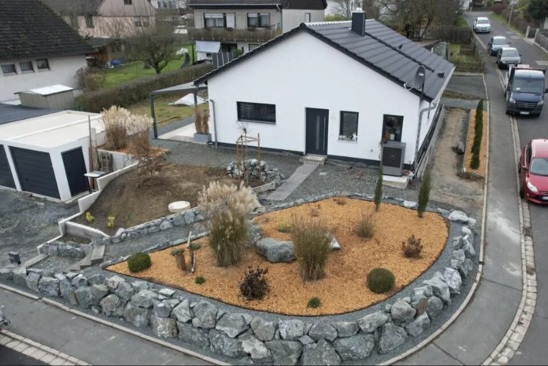 Bungalow mit angelegtem Vorgarten, Natursteinmauer und Beeten, Luftaufnahme